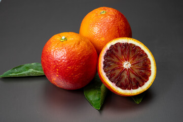 Sicilian sweet juicy yellow and red blood oranges with green leaves close-up