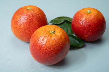 Sicilian sweet juicy yellow and red blood oranges with green leaves close-up