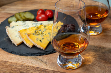 Whiskey and cheese pairing, tasting whisky glasses and plate with sliced crumbly old blue stilton and blue shropshire cheeses, Great Britain food and drink