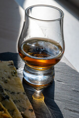 Whiskey and cheese pairing, tasting whisky glass and plate with sliced blue stilton and blue shropshire cheeses, Great Britain food and drink