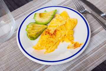 Omelette served for breakfast with sliced avocado on platter