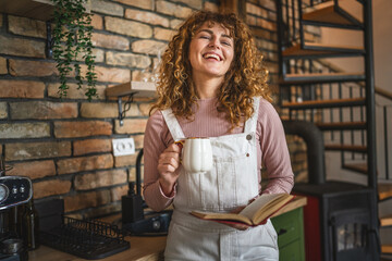 Fototapeta premium beautiful curly hair adult woman stand in kitchen and read a book