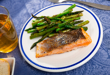 Closeup of grilled spicy salmon serving with asparagus on a ceramic plate at a restaurant