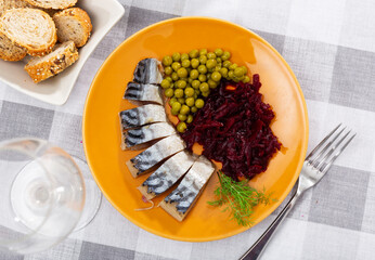 Cold smoked mackerel with grated beetroot and green peas served in a plate with other table appointments
