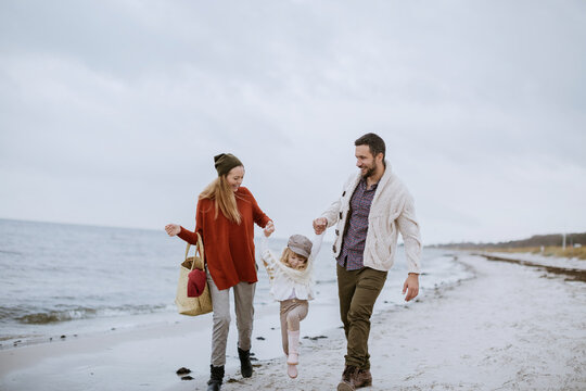 Young family walking on a beach during winter - Powered by Adobe