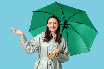 Happy young woman with umbrella on blue background