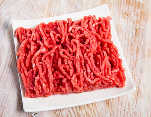 Raw ground meat of pork and beef ready for cooking on wooden surface..