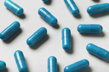 Blue hard capsules on grey background, closeup