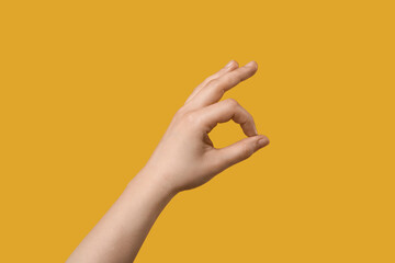 Female hand showing OK on yellow background