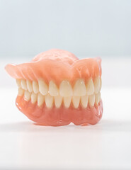 Close-up of a dental prosthetic model with artificial teeth and gums on a wooden surface. Ideal for dental care imagery