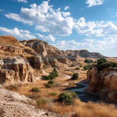 Obraz premium Serene Landscape of Majestic Badlands Under Expansive Blue Sky with Fluffy White Clouds and Lush Green Grass Highlighting Nature's Beauty