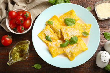 Delicious ravioli with cheese and basil served on wooden table, flat lay