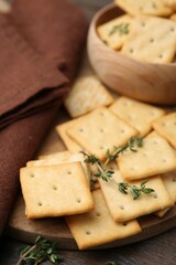 Tasty salty crackers with thyme on wooden table, closeup