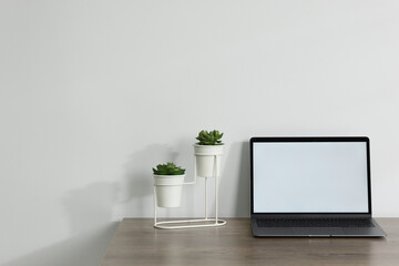 Laptop and floral decor on wooden office table against white background, space for text
