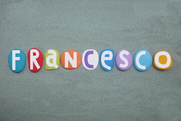 Francesco, masculine italian given name composed with multi colored hand painted stone letters over green letters 