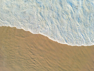 Aerial view of waves lapping the sandy beach