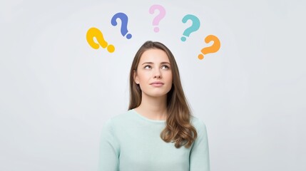 Young woman pondering questions with colorful question marks above her head in a light background.