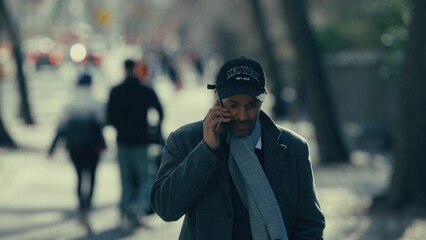 Elegant businessman walking and talking on his phone in a street of Manhattan, New York