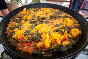 Colourful vegan paella of cauliflower, peppers, green beans and saffron rice bubbles in a paella pan, offering a meat‑free twist on Valencia’s most famous dish.