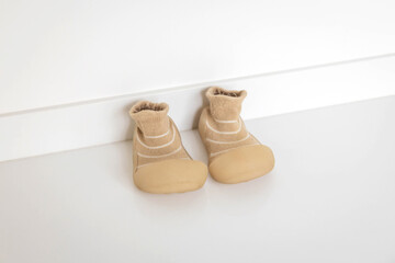 Pair of Soft Beige Baby Shoes with Ribbed Ankle Cuffs on Smooth White Surface