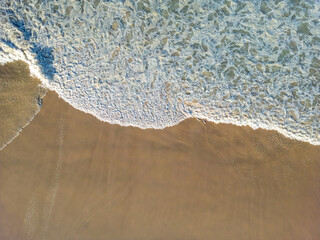 Aerial view of big waves lapping the sandy beach