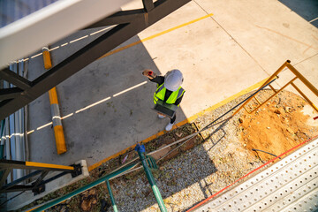 Female engineer inspects solar panels under a carport with a laptop and infrared thermometer. Focus...