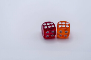 Two colorful translucent dice in orange and red colors on a light surface