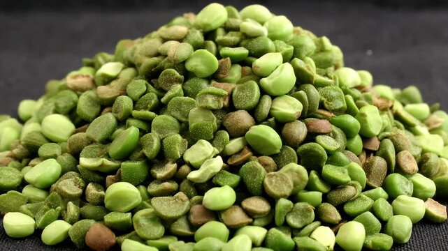 Close-up pile of dried split green peas on a dark background, showcasing their natural texture, color variation, and nutritional value for cooking.
