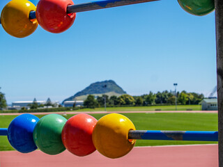 View across Tauranga Domain framed by play equipment from children s playground.