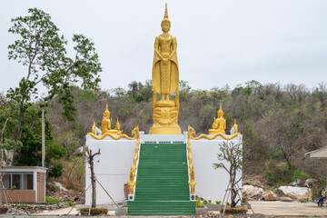 Lopburi, Thailand, April 14, 2025, Majestic yellow Buddha statue at Wat Tamtako amidst lush greenery