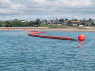 Protecting the environment from oil spills using bright red inflatable boom floating © Brian Scantlebury