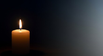 Single candle flame illuminates a dark background.