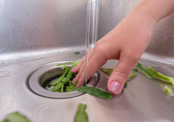 Recycling food scraps: fresh vegetable peels entering a garbage disposal system