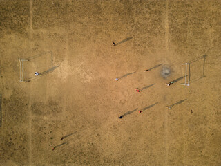 Drone aerial view of a football field in rural Thailand. Local children play football in the evening.