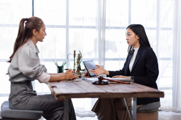 Two lawyers in suits discussing legal matters at a desk with a gavel, scales of justice, and a law book, symbolizing law and justice, justice and lawyer Business partnership meeting concept.
