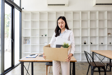 Business woman with box cardboard packing personal items after losing jobs. asian business woman...