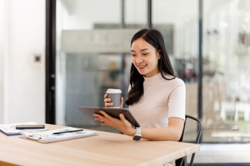 Fototapeta premium Smiling asian woman or accountant working with documents using calculator and tablet computer laptop at the office desk 