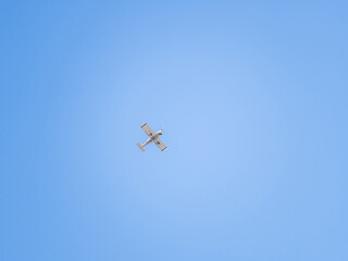 Small ultralight airplane with overhead wing and single propeller flying in sunset sky.