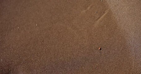 Drawing of sad face etched into sand washed away by sea wave. Impermanent sad smiley drawing creates sense of transient emotion and fleeting moment