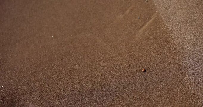Drawing of sad face etched into sand washed away by sea wave. Impermanent sad smiley drawing creates sense of transient emotion and fleeting moment