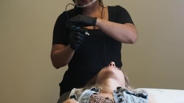 In this transitional moment, the esthetician adjusts her stance and raises the pen while the client remains still. The brief pause reflects rhythm and readiness in the real-time pace of microblading.