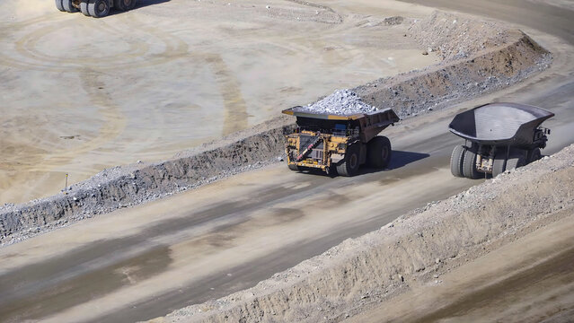 Giant mining trucks transporting minerals in an open pit mine