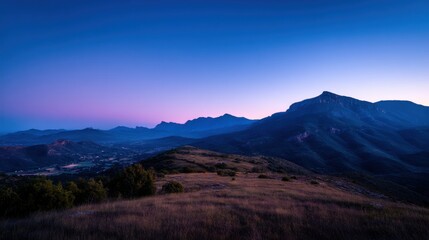Obraz premium Serene Mountain Landscape at Dusk with Vibrant Sky Colors and Gentle Rolling Hills in the Foreground and Majestic Peaks in the Background
