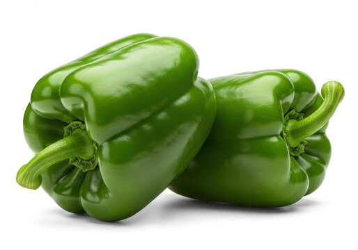 Two fresh green bell peppers stacked against a white background in a studio shot