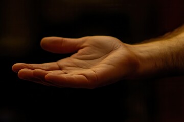 Open hand reaching out in a dimly lit space, symbolizing connection and offering support