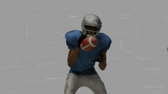 Male football player catching football in studio showing tech overlay with floating binary code - Powered by Adobe