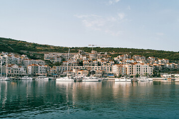 Obraz premium Sailing yachts are moored off the coast of a bay with colorful houses. Lustica, Montenegro