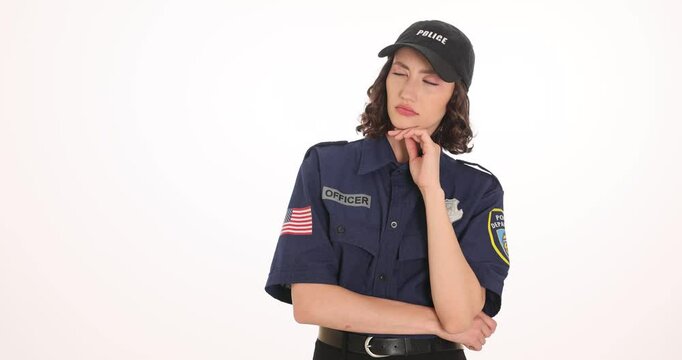 Woman in dark blue police uniform with cap and badge stands with thoughtful look and hand on chin. Police officer at work contemplates information