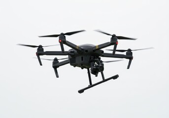 A black drone with a camera attached hovering against a bright white sky in an outdoor setting view