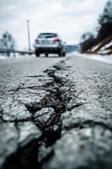 Car Is Driving on Broken Road with Cracked Asphalt
